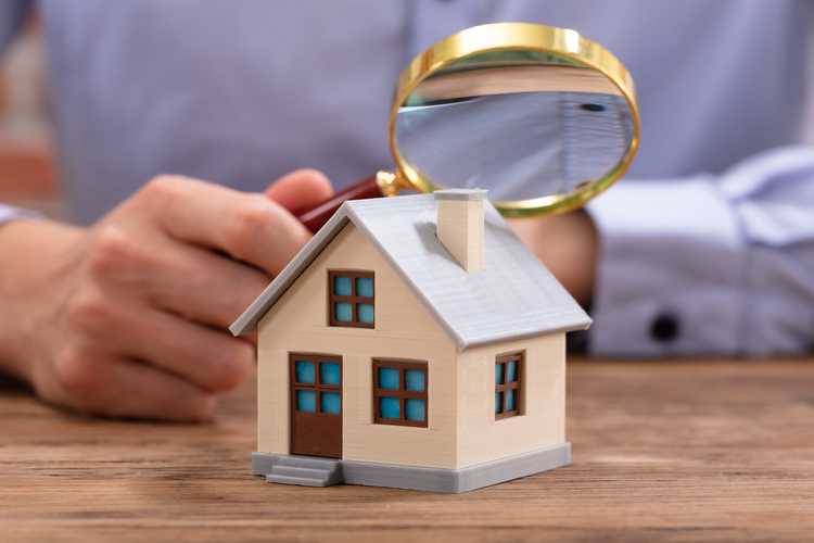 man looking at a model house with a magnifying glass 