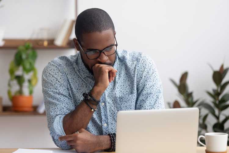 man looking at laptop deciding between stocks or ETFs