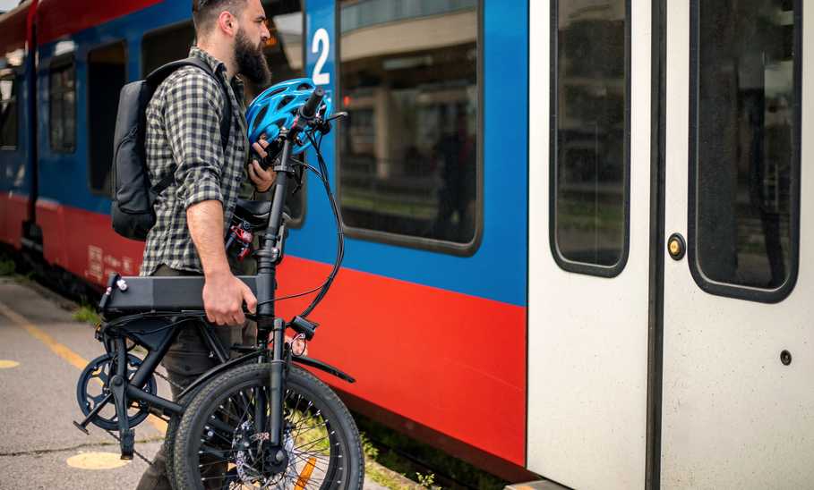 man with folding e-bike getting on train